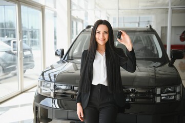 woman showing car key in dealership showroom