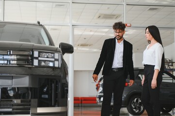 Arab Car salesman showing new vehicle to woman in dealership