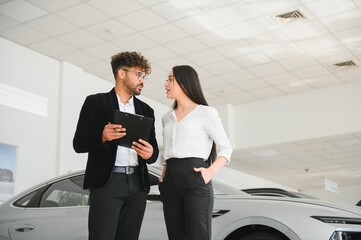 Arab Car salesman showing a new car to a female customer in dealership