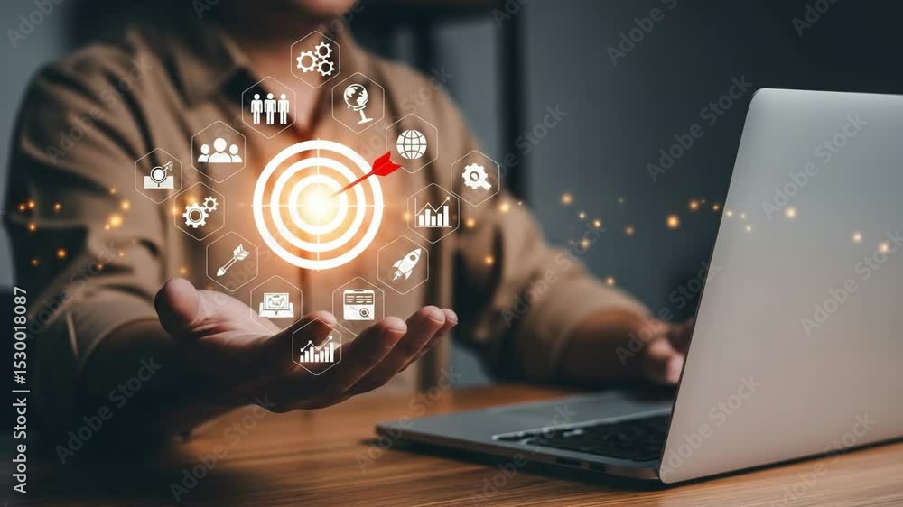 Poster person using laptop with target and business icons floating above hand on a wooden desk surface