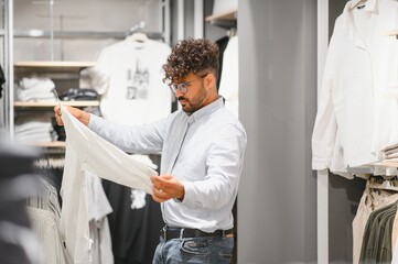 Obraz premium Stylish arab man choosing clothes in fashion store