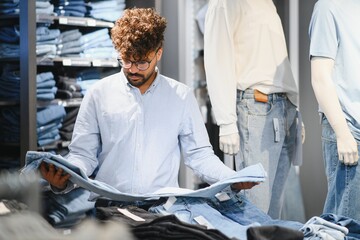 Stylish arab customer choosing jeans in clothing store