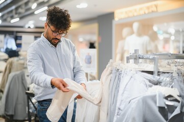 Stylish arab man choosing clothes in fashion store