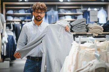 Stylish arab man choosing clothes in fashion store