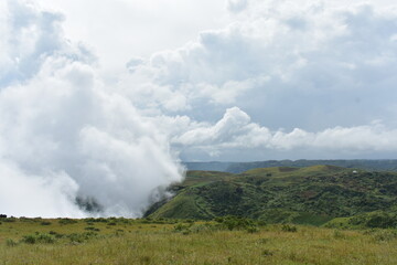 White clouds billow over rolling green hills, expansive sky in Meghalaya. 