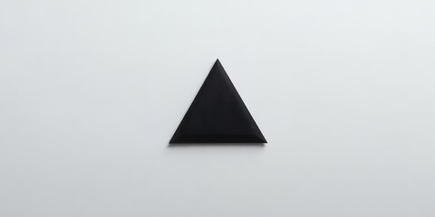 A minimalist image showcasing a single black triangle centered on a plain white background surface