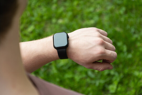 Close up man hands checking his heartbeat with smartwatch at nature park. Male checking pulse after jogging. Fitness tracker - Powered by Adobe