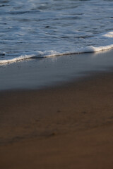 The ocean waves are crashing against the shore, creating a peaceful and calming atmosphere. The water is a mix of white foam and brown sand, giving the scene a serene and tranquil feel