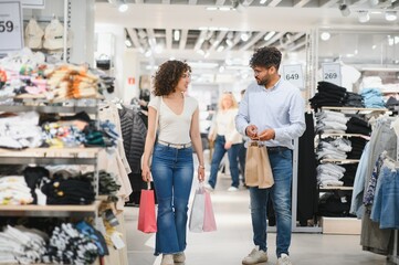 Young couple carrying shopping bags while walking in clothing store