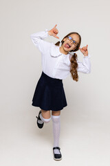 Cheerful funny genius positive little girl with curly hair in a white school blouse, shirt, skirt...