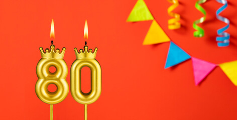 Number 80 birthday candle on an orange background with pennants