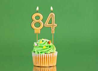 Number 84 birthday candle - Cupcake on a green background