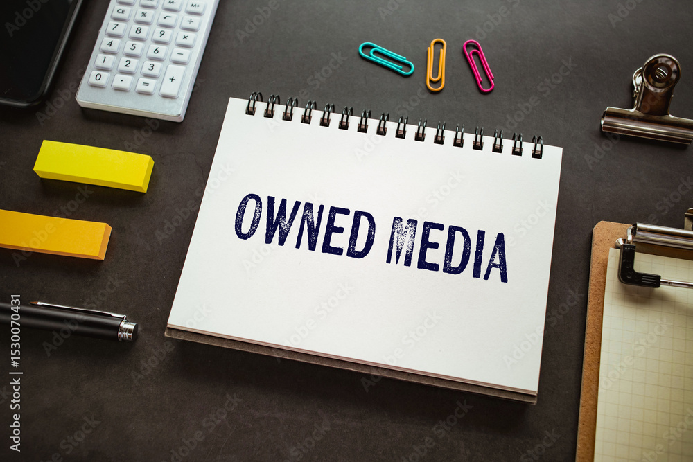 Poster there is notebook with the word owned media. it is as an eye-catching image.