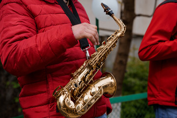 Saxophone Player in Red Puffer Jacket Outdoors, Street Performance, Brass Instrument, Urban Music...