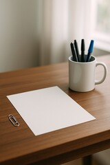 Minimal workspace scene with blank white sheet of paper, pens in a mug, and paperclip on wooden desk by window, conveying simplicity, focus, organization, and quiet productivity

