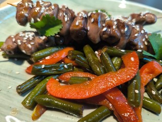 Delicious grilled chicken heart meat skewers served with green salad on the kitchen table