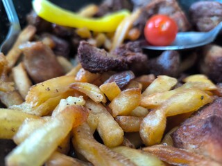 Traditional fried potatoes with pork and mushrooms close-up in a frying pan.