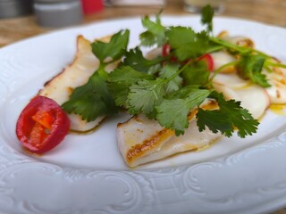 baked squid with herbs and red peppers lie on a plate