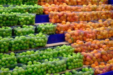 Fresh summer fruits sold in a market. Healthy vegan nutrition. Apricots and green plums close-up. Vitamin store, apricot, plum. Vegetable and fruit prices in the greengrocer's. Organic farming.