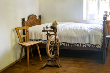 A spinning wheel beside the old bed