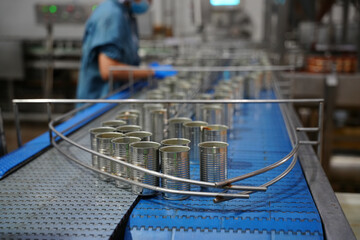 Cans move along production line in food processing facility during work shift