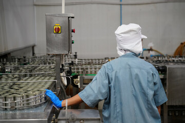 Worker monitoring canning machine in food processing facility during operational hours