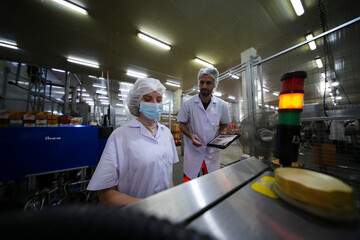 Workers in food processing facility inspect machines while practicing safety protocols