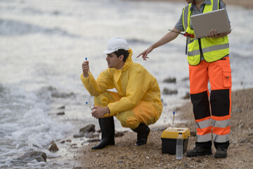 Environmental scientists collect water samples at the beach during a sunny day for analysis of marine health