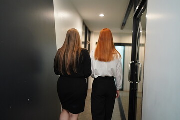 Two women walking through a modern hallway in a stylish office setting