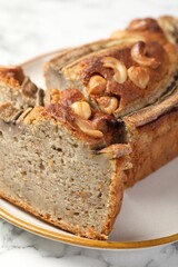 Cut banana bread with nuts on white marble table, closeup