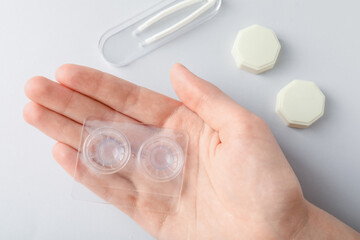 Woman with contact lenses on light background, flat lay