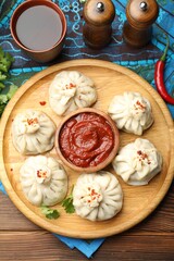 Delicious khinkali served with sauce on wooden table, flat lay