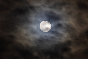 Full moon in the dark night sky with clouds 