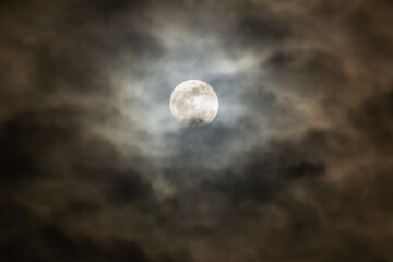 Full moon in the dark night sky with clouds 