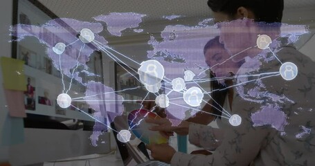 Women tapping tablet adjusting color wheel animating translucent world map overlay informing design - Powered by Adobe