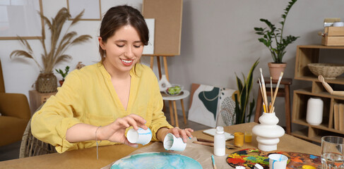 Beautiful artist creating fluid art painting in workshop