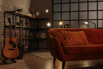 Interior of dark living room with glowing lamps, sofa and shelving unit