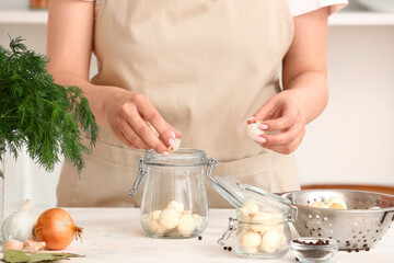 Woman preparing mushrooms for canning at table in kitchen