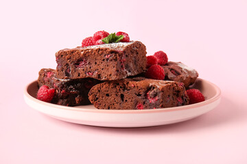 Plate with pieces of raspberry chocolate brownie on pink background
