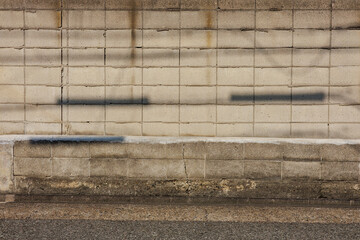 Light gray hued concrete block wall composed of rectangular blocks, arranged in a grid pattern....