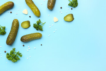 Pickled cucumbers and different spices on blue background