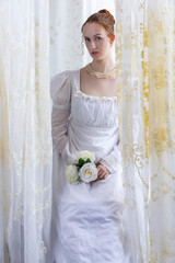 A Regency period woman wearing a white embroidered cotton dress and surrounded by backlit lace...