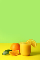 Glass of fresh orange juice on colorful background