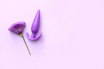 Anal plug from sex shop and beautiful eustoma flower on purple background