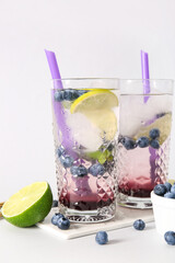 Glasses of fresh blueberry lemonade on white background