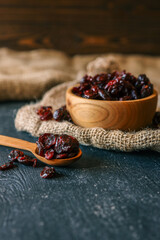 Dried cranberries on a wooden spoon and in a bowl, placed on rustic burlap fabric. These tangy, sweet fruits are rich in antioxidants and often used in snacks, salads, and baking