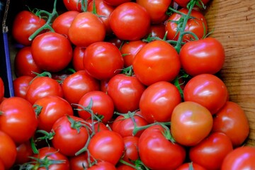 Fresh summer vegetables sold in the market, bunch tomatoes. Healthy vegan nutrition. Red fresh tomatoes. Blood-forming tomatoes. Fruit and vegetable prices in the greengrocer's. Organic farming.