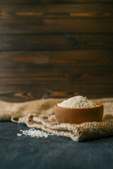 Semolina in a wooden bowl placed on a rustic burlap cloth with some grains spilled on a dark surface. Warm natural tones and texture-rich setup
