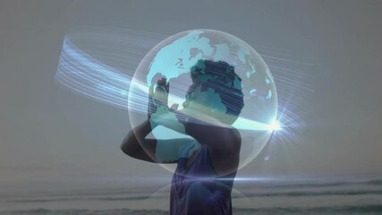 Woman raising arms at ocean edge powering digital globe with swirling light trails for health - Powered by Adobe