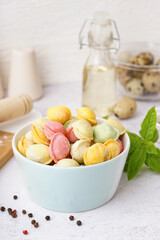Bowl of colorful raw dumplings with peppercorn and basil on white background